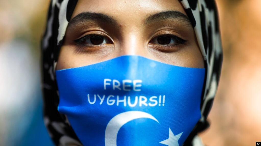 FILE - A woman wears a face mask reading "Free Uyghurs" as she attends a protest during the visit of Chinese Foreign Minister Wang Yi in Berlin, Sept. 1, 2020. 
