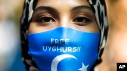 资料照片：中国外交部长王毅访问柏林期间，一名参加抗议活动的妇女戴着写有“释放维吾尔人”英文字样的口罩。（2020年9月9日）