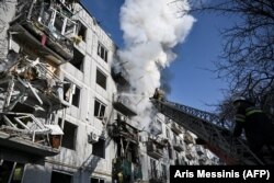 Petugas pemadam kebakaran berusaha memadamkan api di sebuah gedung setelah pemboman di kota Chuguiv di Ukraina, 24 Februari 2022. (Foto: AFP/Aris Messinis)