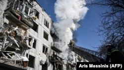 Petugas pemadam kebakaran bekerja pada kebakaran di sebuah gedung setelah pemboman di kota Chuguiv di Ukraina, 24 Februari 2022, saat Rusia mencoba menyerang Ukraina. (Foto: AFP/Aris Messinis)