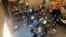 FILE - Migrants released by the Border Patrol with notices to appear in court, Feb. 5, 2022, in Somerton, Ariz., wait for COVID-19 testing at a Regional Center for Border Health warehouse.