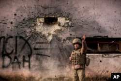 Ukrajinski vojnik pokazuje u pravcu odakle je izvršeno ganatiranje, ispred kuće koju je pogodila granata velikog kalibra, u selu Krimske na liniji razdvajanja, u regionu Lugans, istočna Ukrajina, 19. februara 2022.