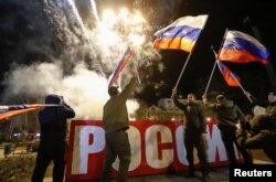 Pro-Russian activists react in a street as fireworks explode in the sky, after Russian President Vladimir Putin signed a decree recognising two Russian-backed breakaway regions in eastern Ukraine as independent entities, in the separatist-controlled city