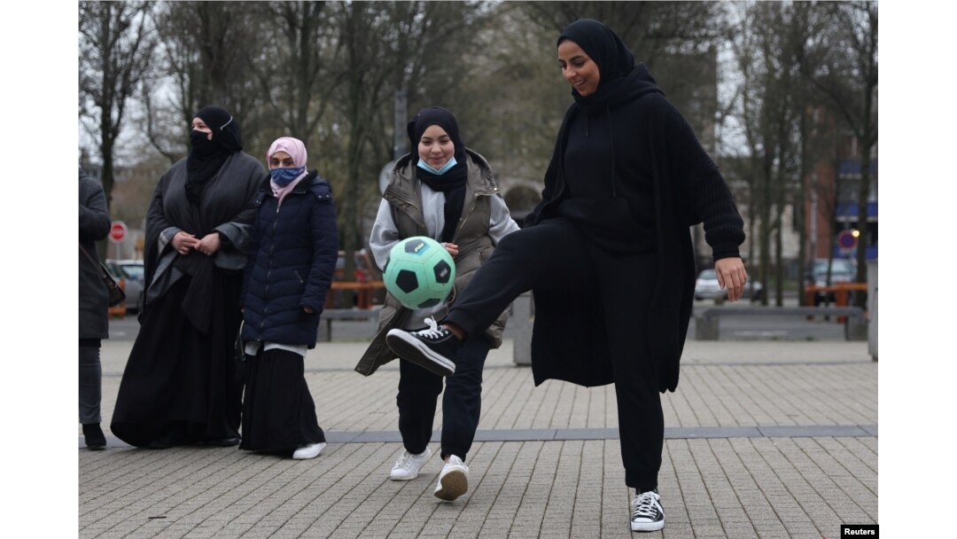 Pendukung tim sepak bola perempuan "Les Hijabeuses" bermain sepak bola di depan balai kota di Lille, sebagai bagian dari protes saat Senat Prancis memeriksa RUU yang menampilkan larangan hijab kontroversial dalam olahraga kompetitif di Prancis, 16 Februari 2022. (REUTERS/Pascal Rossignol)
