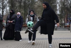 Pendukung tim sepak bola perempuan "Les Hijabeuses" bermain sepak bola di depan balai kota di Lille, sebagai bagian dari protes saat Senat Prancis memeriksa RUU yang menampilkan larangan hijab kontroversial dalam olahraga kompetitif di Prancis, 16 Februari 2022. (REUTERS/Pascal Rossignol)