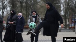 Foto ilustrasi yang menunjukkan sejumlah perempuan berhijab bermain bola di depan balai kota Lille, Prancis, sebagai bentuk protes atas pelarangan hijab dalam kompetisi olahraga di Prancis, pada 16 Februari 2022. (Foto: Reuters/Pascal Rossignol)