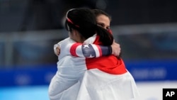 Gold medal winner Miho Takagi of Japan hugs bronze medalist Brittany Bowe of the United States, facing right, after the women's speedskating 1,000-meter finals at the 2022 Winter Olympics, Feb. 17, 2022, in Beijing.
