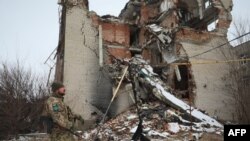 A serviceman of Ukrainian military forces walks in front of destroyed building on the front line with Russia-backed separatist in Mariinka, Donetsk region on February 7, 2022. (Photo by Aleksey Filippov / AFP)