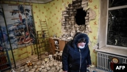 A woman stands inside among debris after the reported shelling of a kindergarten in the settlement of Stanytsia Luhanska, Ukraine, on Feb. 17, 2022.