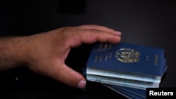 Beneficiario de una Visa Especial de Inmigrante (SIV) de EE.UU., tiene los pasaportes de su familia mientras firman un contrato de arrendamiento en un nuevo apartamento luego de su evacuación de Afganistán en Houston, Texas, EE. UU., 26 de agosto de 2021.