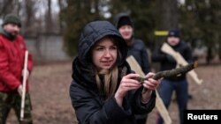 Una residente aprende a apuntar y disparar con un palo de madera mientras participa en un ejercicio militar para civiles realizado por Christian Territorial Defense, en medio de una amenaza de invasión rusa en Kiev, Ucrania, el 19 de febrero de 2022.