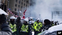 Police clear protesters from downtown Ottawa, Feb. 19, 2022. Police resumed pushing back protesters on Saturday after arresting more than 100 and towing vehicles in Canada’s besieged capital.