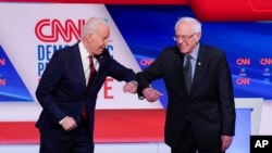 Mantan wakil presiden AS Joe Biden (kiri) dan Senator Bernie Sanders (kanan) bersalaman dalam debat pemilihan pendahuluan di Washington D.C, 15 Maret 2020.