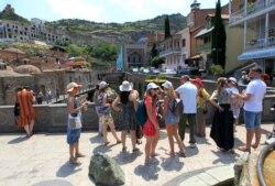 FILE - FILE - A group of Russian tourists listen to a guide in the Old Town section of Tbilisi, Georgia, June 22, 2019.