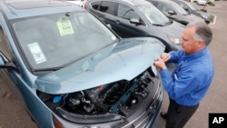 FILE - A sales manager at a Honda car dealership, opens the hood of a Honda CRV SUV, Dec. 2, 2014, in Tempe, Arizona. 