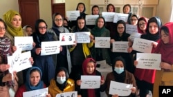 FILE -Afghan women chant and hold signs of protest, in Kabul, Afghanistan, Dec. 27, 2021.