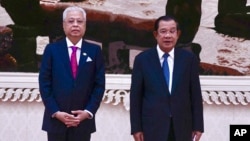 Cambodian Prime Minister Hun Sen, right, poses for photographs together with his Malaysian counterpart Ismail Sabri Yaakob, left, during his visit to Cambodia in Phnom Penh, Cambodia, Thursday, Feb. 24, 2022. (Kok Ky/Cambodia's Government Cabinet via AP)