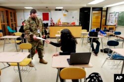 Substitute teacher and New Mexico Army National Guard specialist Michael Stockwell takes a geology assignment from Lilli Terrazas, 15, at Alamogordo High School.