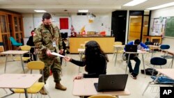 Substitute teacher and New Mexico Army National Guard specialist Michael Stockwell takes a geology assignment from Lilli Terrazas, 15, at Alamogordo High School.