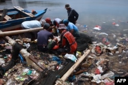 FILE - Fishermen sort their catch from a net as they fish in polluted waters filled with plastic waste in Bandar Lampung, Feb. 21, 2022.