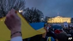 People hold a giant Ukrainian flag during a vigil to protest the Russian invasion of Ukraine in front of the White House in Washington, Feb. 24, 2022.