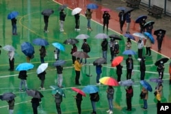 FILE - Residents line up to get tested for the coronavirus at a temporary testing center despite the rain in Hong Kong, Feb. 22, 2022.