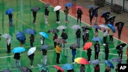 FILE - Residents line up to get tested for the coronavirus at a temporary testing center despite the rain in Hong Kong, Feb. 22, 2022.