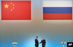 Russian President Vladimir Putin, right, and Chinese President Xi Jinping shake hands at the opening ceremony of the Year of Chinese Tourism in Russia, at the Kremlin in Moscow.  (Photo: AP)