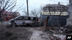 A damaged vehicle and debris following Russian shelling outside outside Mariupol, Ukraine, Thursday, Feb. 24, 2022. Russia has launched a barrage of air and missile strikes on Ukraine early Thursday. (AP Photo/Sergei Grits)