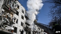Vatrogasci gase požar u zgradi nakon što je pogođena bombom, u gradu Čugujevu, na istoku Ukrajine, 24. februara 2022, nakon što su ruske snage započele invaziju na tu zemlju.