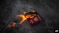 Protesters burn a Russian passport to demonstrates against Russian attacks in Ukraine in front of the Russian embassy in Vilnius, Lithuania, Feb. 24, 2022. 