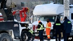 Para petugas polisi membantu operator derek kendaraan untuk memindahkan truk yang terparkir di Nicholas Street, Ottawa, Kanada, pada 18 Februari 2022. (Foto: The Canadian Press via AP/Justin Tang)