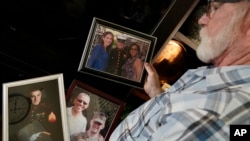 FILE - Joey Reed holds photos of his son Marine veteran and Russian prisoner Trevor Reed at his home in Fort Worth, Texas, Feb. 15, 2022.