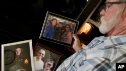 Joey Reed holds photos of his son Marine veteran and Russian prisoner Trevor Reed at his home in Fort Worth, Texas, Feb. 15, 2022.