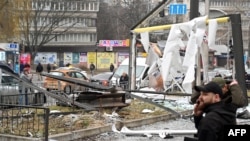 Polisi dan petugas keamanan berkumpul di dekat puing-puing peluru yang mendarat di jalanan kota Kyiv, Ukraina, pada 24 Februari 2022. (Foto: AFP/Sergei Supinsky)
