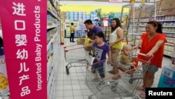 FILE - A family looks at foreign imported milk powder products at a supermarket in Beijing, July 3, 2013.