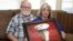 Joey and Paula Reed pose for a photo with a portrait of their son Marine veteran and Russian prisoner Trevor Reed at their home in Fort Worth, Texas, Feb. 15, 2022. Russia is holding Reed, who was sentenced to nine years on charges he assaulted a police officer.