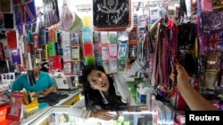 FILE - A vendor serves a customer at her shop selling mobile phones and accessories at Bangkok's MBK mall, Sept. 17, 2010. 