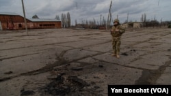 Un soldado ucraniano observa el lugar donde cayó una bomba que mató a otro soldado no lejos de la línea del frente en el este de Ucrania, el 19 de febrero de 2022, en Novoluganske, Ucrania. (Yan Boechat/VOA)
