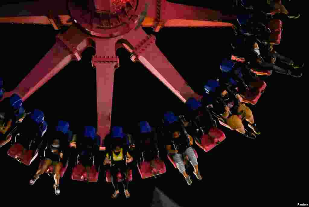 People wearing face masks as protection against COVID-19 ride a frisbee during the reopening of an amusement park in Pasay City, Metro Manila, Philippines.