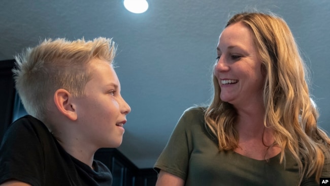 Colton Nover, 10, laughs with his mother, Holly Nover, in their kitchen Wednesday, Feb. 16, 2022, in St. Johns, Fla. (AP Photo/Fran Ruchalski)