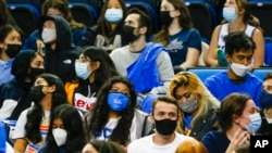 Fans wearing face masks watch a college basketball game in Los Angeles, Feb. 17, 2022.