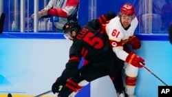 China's Wei Ruike (Ethan Werek) (61) is checked by Canada's Morgan Ellis (5) during a men's qualification round hockey game at the 2022 Winter Olympics, Feb. 15, 2022, in Beijing.