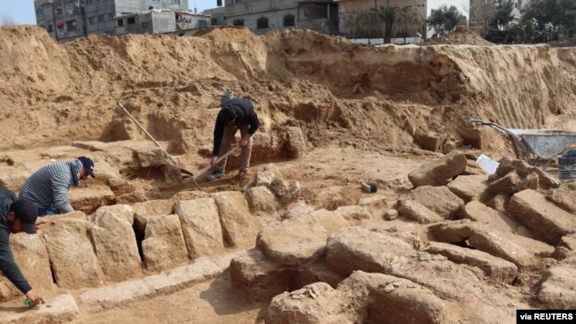 Men work in a newly discovered Roman cemetery in Gaza, in this handout photo obtained by Reuters, February 17, 2022. Ministry of Tourism and Antiquities/Handout via REUTERS 