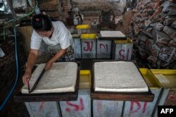 A worker cuts tofu at a factory in Surabaya on February 21, 2022, amid a slowdown of production in the country due to soaring prices of soybean in world markets.