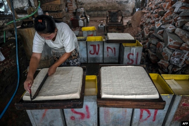 A worker cuts tofu at a factory in Surabaya on February 21, 2022, amid a slowdown of production in the country due to soaring prices of soybean in world markets.