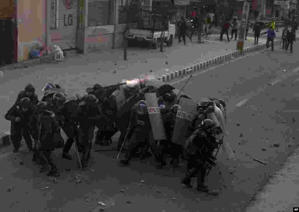 Nepalese policemen take cover as protesters opposing a proposed U.S. half billion dollars grant for Nepal, hurls stone outside the parliament that debates the contentious aid in Kathmandu.