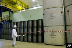 FILE - A worker checks the radiation level on barrels in a storage of nuclear waste taken from the 4th unit destroyed by explosion at the Chernobyl Nuclear Power Plant, in Chernobyl, Ukraine, March 23, 2016.