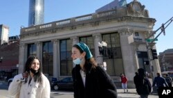 Transeúntes llevan las mascarillas bajo el mentón en Boston, el 9 de febrero de 2022.