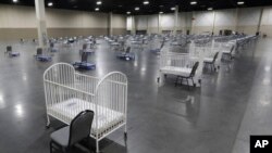 FILE - Cots and cribs are arranged at the Mountain America Expo Center in Sandy, Utah, on April 6, 2020, as an alternate care site or for hospital overflow amid the COVID-19 pandemic. 